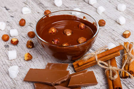 Bowl of melted milk chocolate with hazelnuts next to other sweets