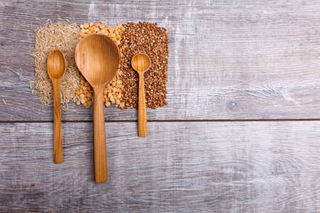 Three different spoons lie on the vertical strips of cereals from aboveの写真素材