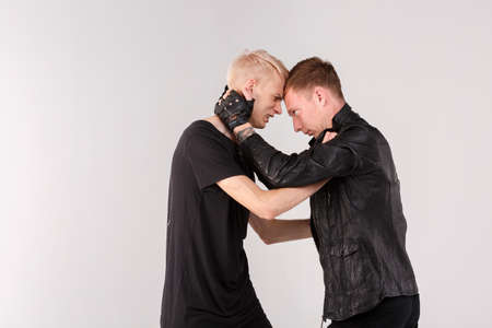 Two guys are fighting. A guy with dark hair dominates and hurts another. Isolation.の写真素材