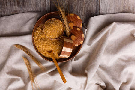 Corn porridge in a wooden plate with wheat spikes on a cloth on a close-up tableの写真素材