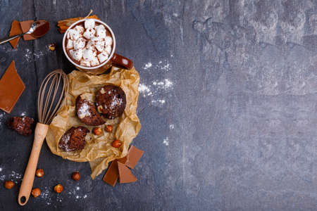 A cup of hot chocolate with marshmallows with sweets around on a stone backgroundの写真素材