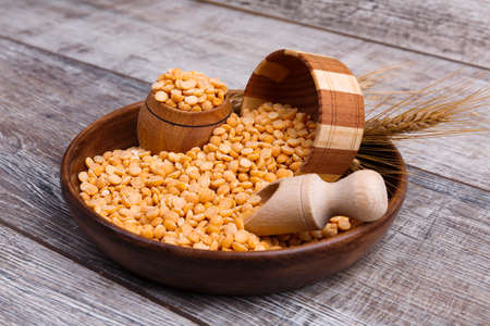 Peas in a wooden plate with a pot on the tableの写真素材