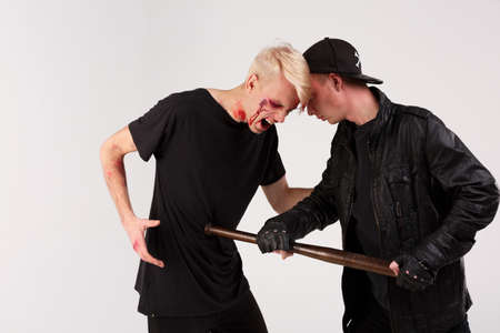 A dangerous guy beats a defenseless guy with a wooden bat. Isolation.の写真素材
