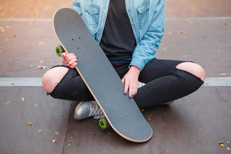 A girl is holding a skateboard in her arms in a skate parkの写真素材