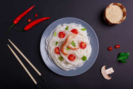 The dish of rice noodles with royal prawns near a slice of mushroom, and two pods of chili . View from above.の写真素材