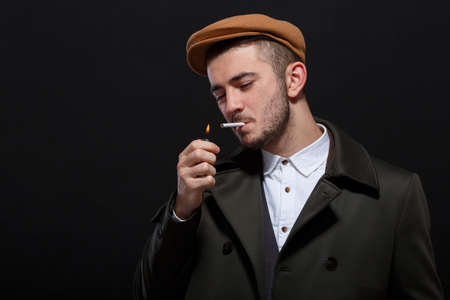Retro style, man light a cigarette on a black backgroundの写真素材