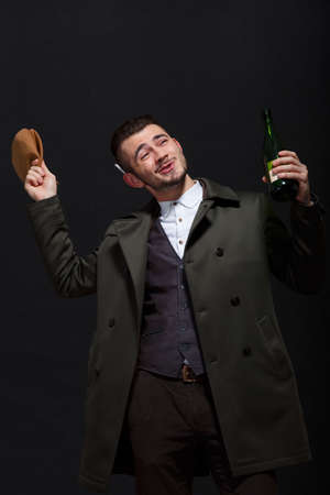 A man on a black background holds in his hand a bottle with a brown capの写真素材