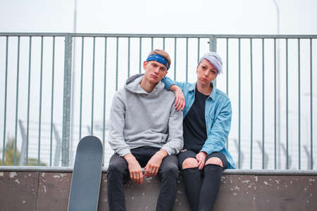 A girl with a guy are sitting on a dispersal in a skate parkの写真素材