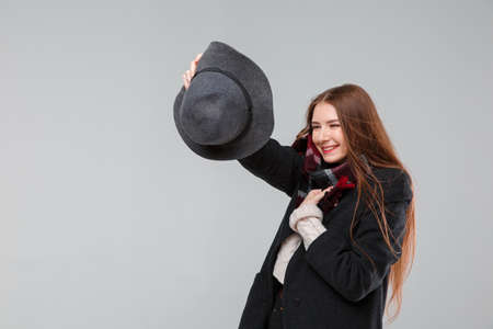 Attractive girl in the studio on a black background smiling with a hat from the windの写真素材