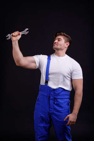 The employee raised the wrench to the level of the head on a black backgroundの写真素材