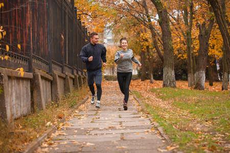 The couple runs in the autumn park. Outdoors.の写真素材