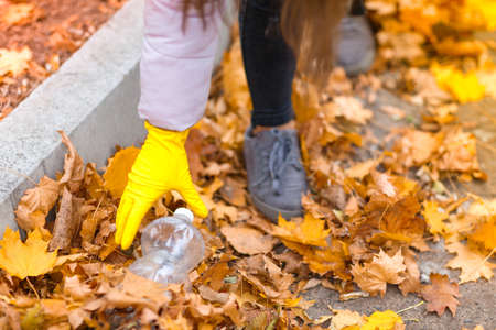Girl raises garbage in an autumn park close upの写真素材