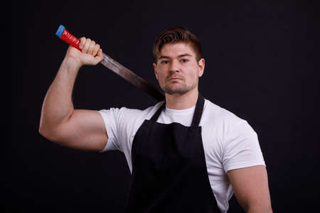 A man holds a machete by the shoulder on a black backgroundの写真素材