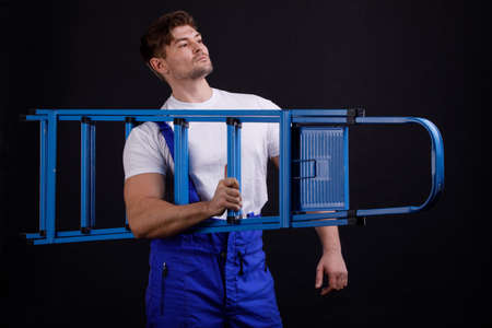 Man with a ladder in his hand on a black background