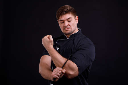 A man pumped up put a knife to his hand on a black backgroundの写真素材