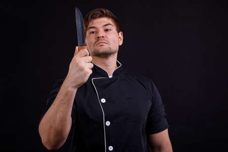 Man is looking at a knife in his hand close-up on a black backgroundの写真素材