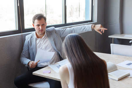 The evil boss in the office points the young girls finger at the exit.の写真素材