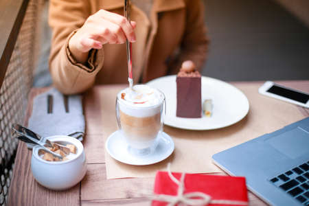 Close-up of a girl in a cafe stirs latteの写真素材