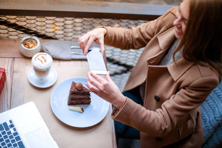Young, girl in outdoor cafe takes a piece of cake.の写真素材