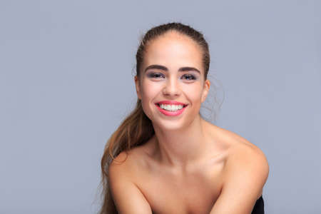 Portrait of a young woman on a light gray background, smiling, cosmeticsの写真素材