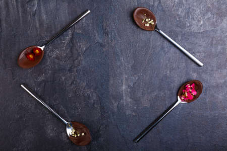 Spoons with frozen chocolate and flowers on them, spoons lies in the shape of a rectangle on the tableの写真素材