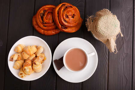 Tea with milk, a plate with bagels and two buns. On a table. View from above. Indoors.の写真素材