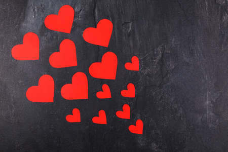 Red hearts of different sizes go from the smaller to the larger diagonally to the left on a stone backgroundの写真素材