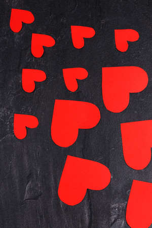 Red hearts of different sizes go from a smaller to a larger diagonal to the right down close-up on a stone backgroundの写真素材