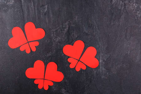 Red hearts carved in different sizes lined up in butterflies close-up on a stone background. View from aboveの写真素材