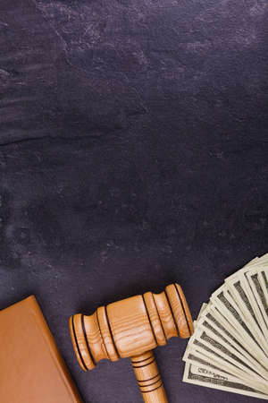 The brown notepad, the wooden hammer of the judge and a bundle of dollars lay with a fan on the bottom against a stone background. View from aboveの写真素材