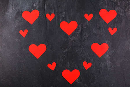 The hearts are red, carved in different sizes, lined up in one big heart on a stone backgroundの写真素材