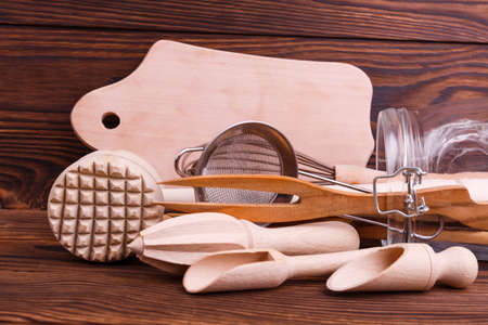 Wooden kitchen tools in a jar mallet, sieve, stingy, wooden dostochka lie on a brown backgroundの写真素材