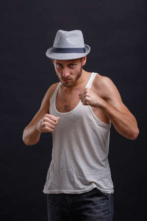 A man in a hat stood in a fighting stance on a black backgroundの写真素材