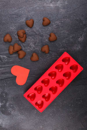 Confectionery silicone red form next to candies in the form of hearts and carved ser on a stone background. View from above...の写真素材