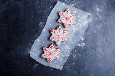 Cookies on parchment in the form of snowflakes sprinkled with powder on a stone background. View from aboveの写真素材