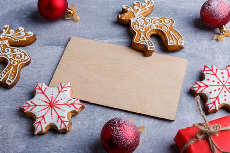 Wooden plank next to cookies in the form of deer and snowflakes, Christmas toys and a gift on a stone backgroundの写真素材