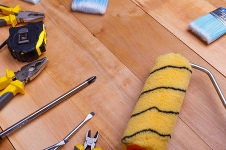 Tools pliers, screwdrivers, tape measure, brushes and roller for small repairs scattered close-up on a wooden backgroundの写真素材