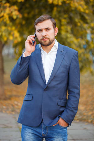 The guy is talking on the phone in the autumn parkの写真素材