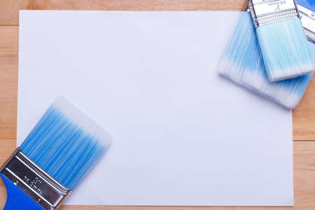 Brushes blue different in size are directed at each other on a piece of paper on a wooden backgroundの写真素材