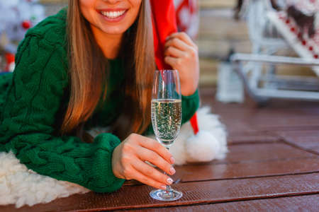 Close-up of a young girl in a santa hat, her smile, with a glass of champagne in her hands.の写真素材