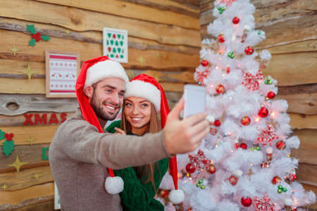 A married couple makes selfie on the background of a Christmas tree.