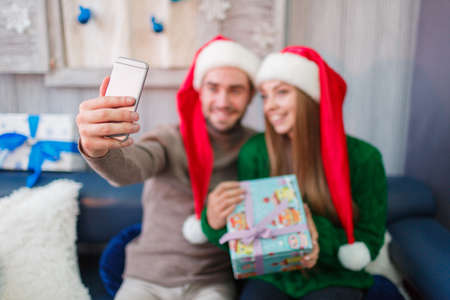 Happy young couple smiling, do selfie, girl holding gift box in hands.