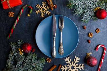 Around plate with a fork and knife there are many different Christmas decorations. View from above.の写真素材