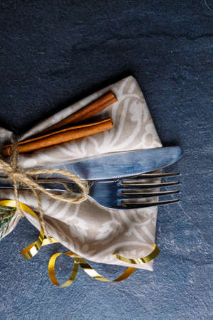 The cutlery decorated with a cinnamon stick and a twig of a Christmas tree.