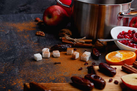 On a table, sugar, cinnamon, a saucepan, a plate with cranberries, a board with dates. Side view. Close up.の写真素材