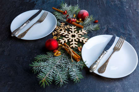 The decorated Christmas tree branch between two plates with cutlery.の写真素材