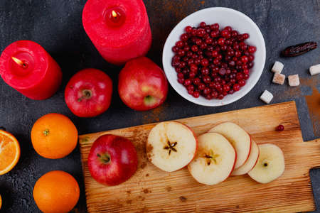 On the table, slices of apples, whole apples and an orange, a plate with cranberries and candles. View from above.の写真素材