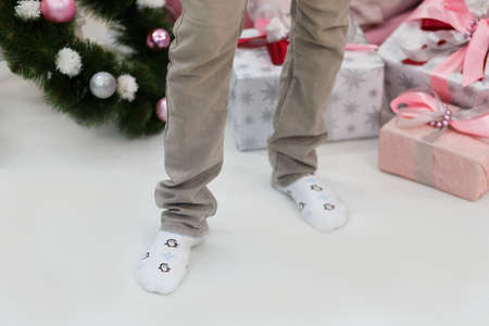 Male legs in white socks with a pattern of penguins. Indoor.の写真素材