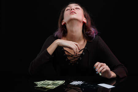 A girl junkie throws her head back, kicks off drugs. On a black background.の写真素材