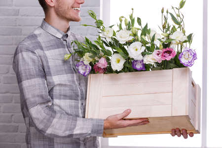 A guy is holding a wooden box with Japanese roses on a white background. Side viewの写真素材